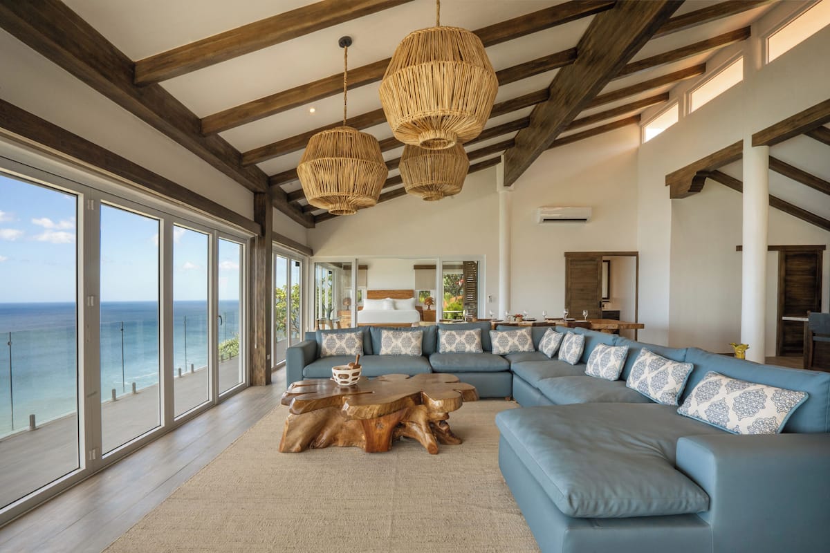 A spacious living room with a large sectional sofa, wooden coffee table, and a view of the ocean.