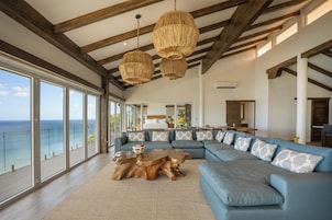 Amplia sala de estar con un sofá modular grande, una mesa de centro de madera y vista al océano.