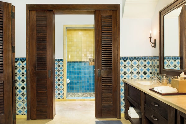 A bathroom with wooden doors, a sink, a mirror, and patterned tiles. - Rancho Santana (Tola)
