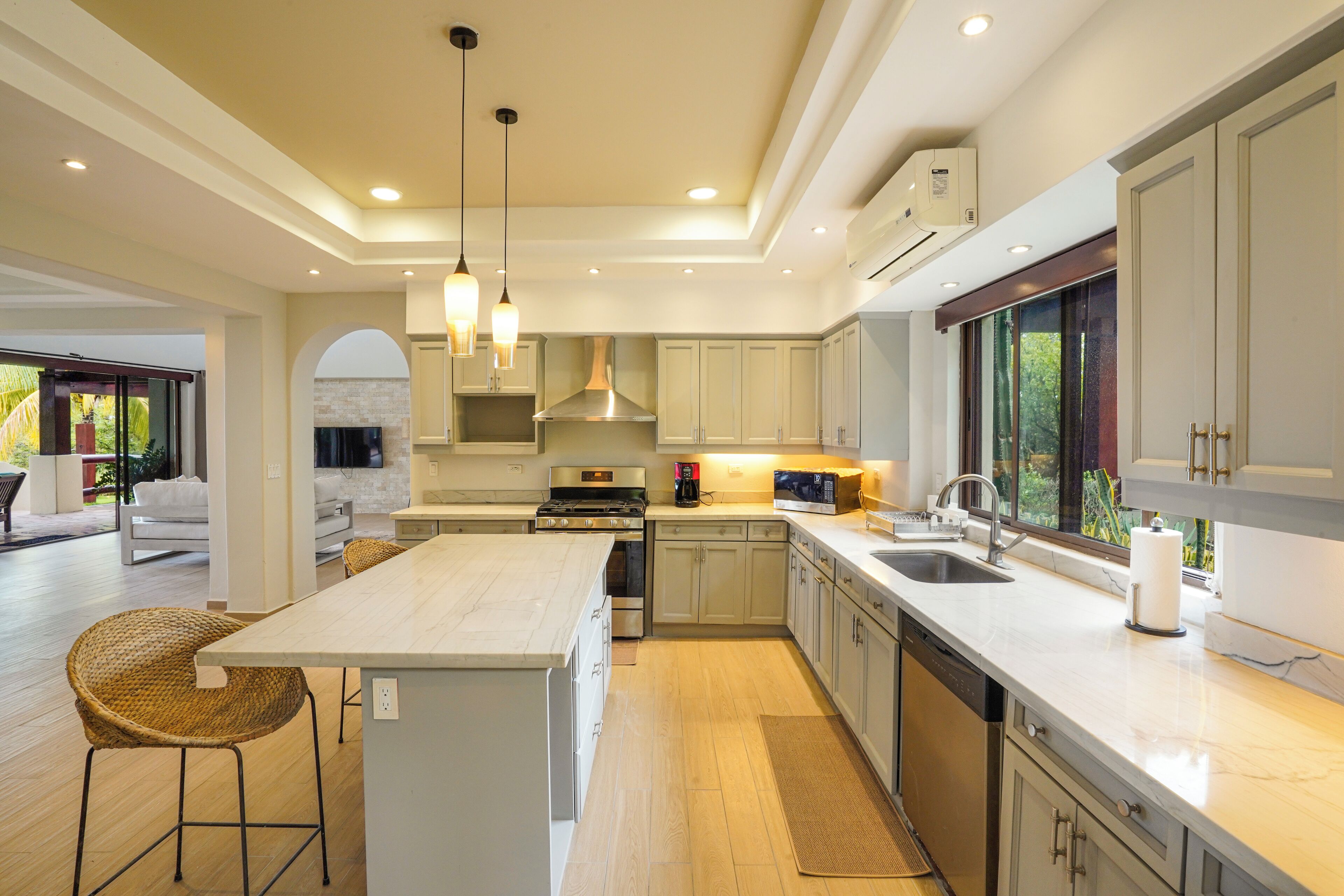A modern kitchen with a central island, stainless steel appliances, and a large window providing a view of the outdoors.
