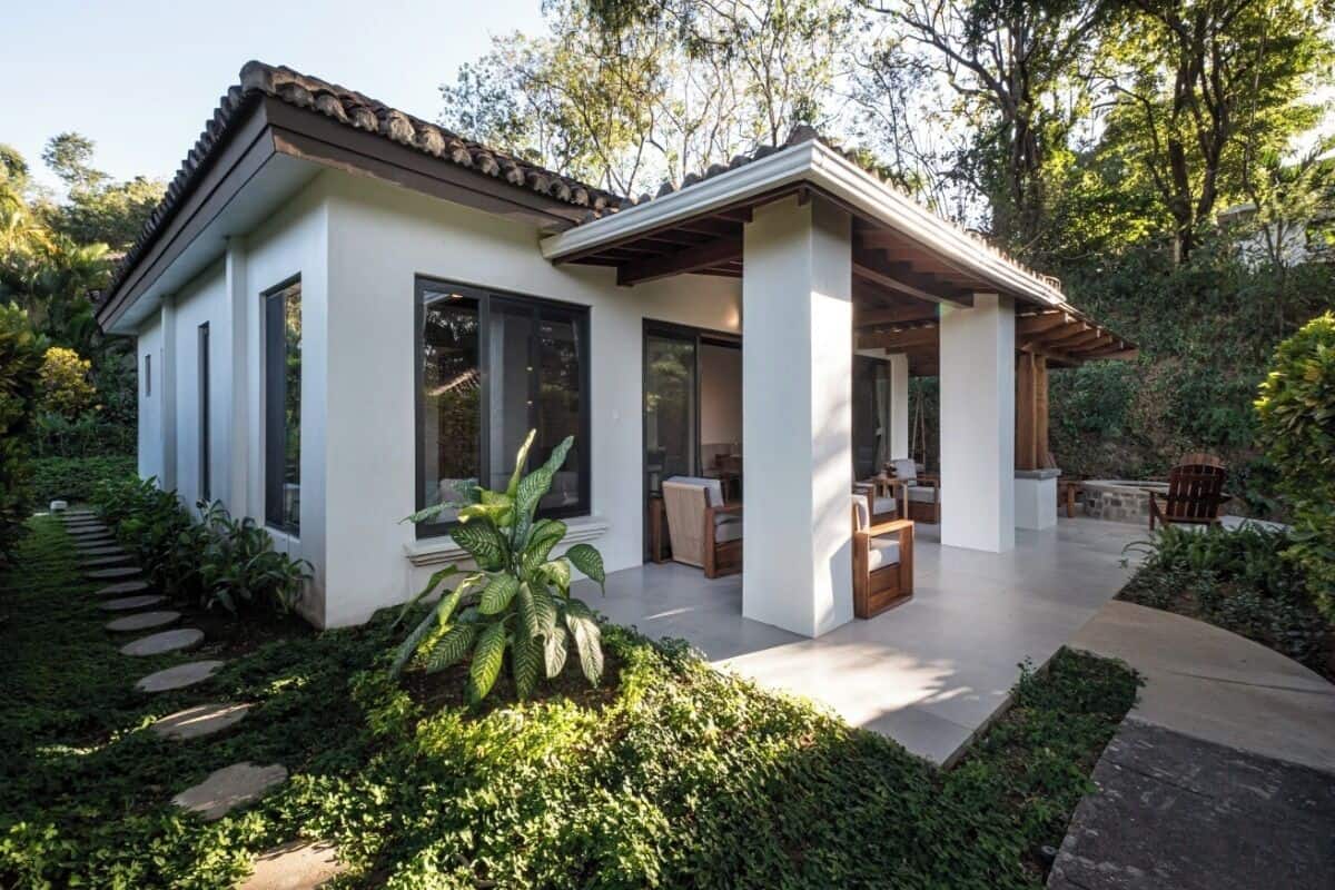 A modern house with a patio, large windows, and a garden.