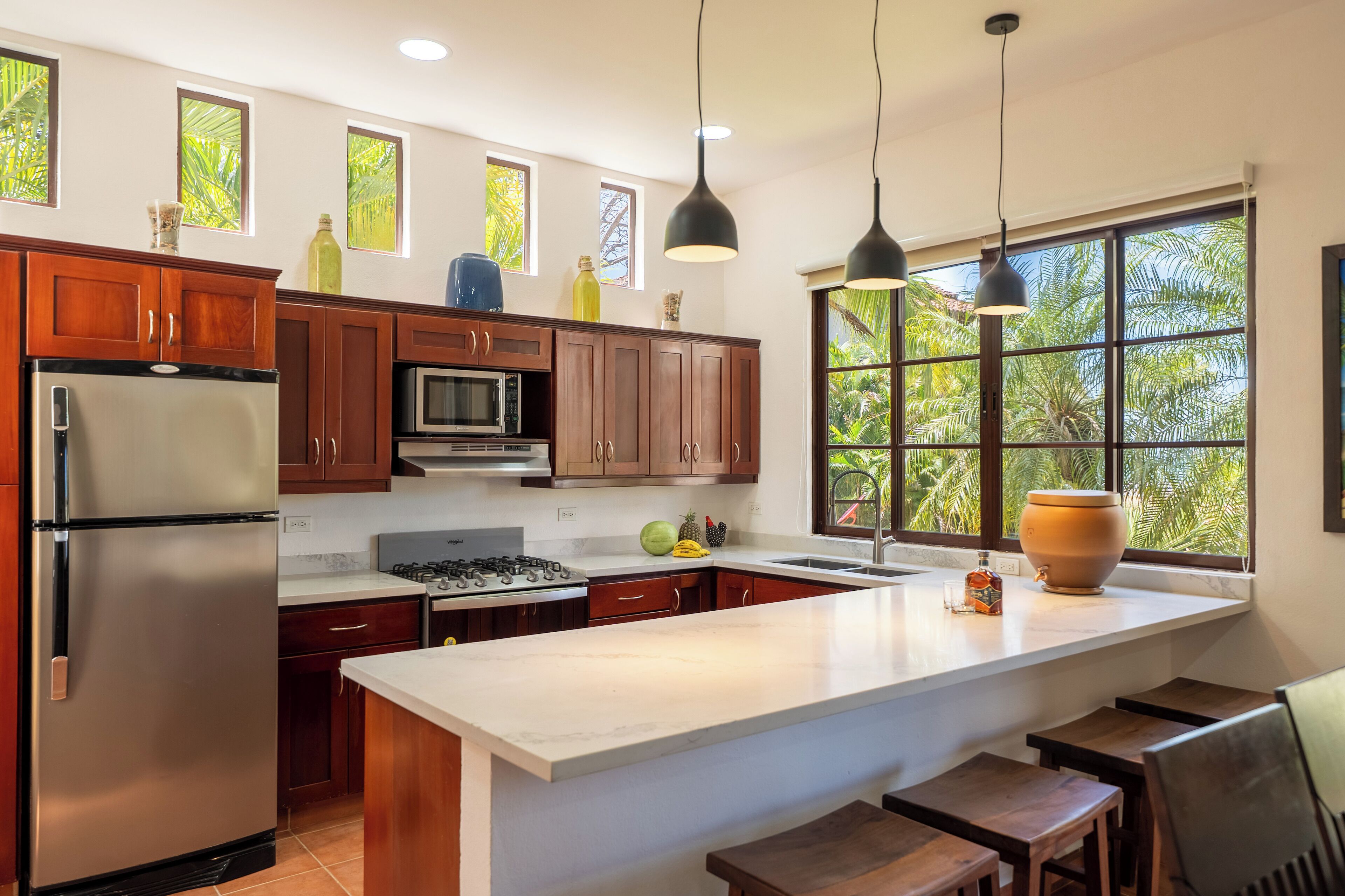 Una cocina moderna con armarios de madera, electrodomésticos de acero inoxidable y un ventanal con vistas al verdor.
