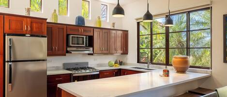 Una cocina moderna con armarios de madera, electrodomésticos de acero inoxidable y un ventanal con vistas al verdor.