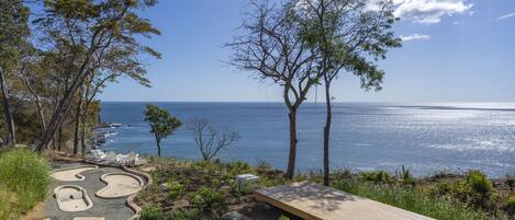 A coastal view with a wooden deck, a winding path, and a bench.