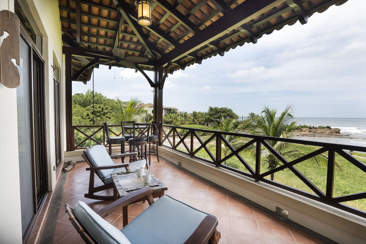 A balcony with a view of the ocean, furnished with a table and chairs, and a railing.