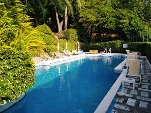 A swimming pool with lounge chairs and a tiled deck. - Eurotel 312 (Rapallo)