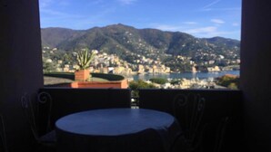 A balcony with a table and chairs, overlooking a cityscape with mountains and a body of water. - Eurotel 312 (Rapallo)