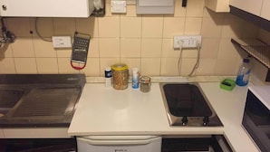 A kitchen with a stove, sink, and a small refrigerator. There are various kitchen items on the counter, including jars and a bottle. - Eurotel 312 (Rapallo)
