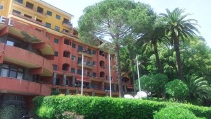 A multi-story hotel with balconies, surrounded by lush greenery and palm trees. - Eurotel 405 (Rapallo)