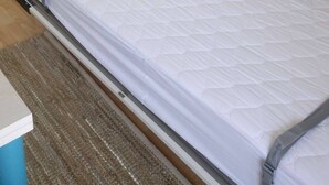 A single bed with a mattress and a grey bed frame in a room with a wardrobe, a small shelf, and a television on the wall. - Eurotel 405 (Rapallo)