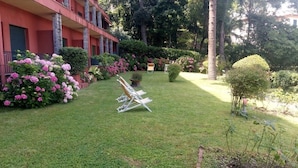 A well-maintained garden with a lawn, seating area, and a building with balconies. - Eurotel 405 (Rapallo)