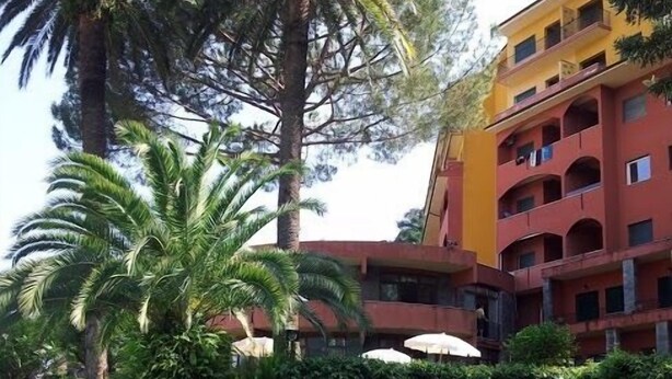 A swimming pool surrounded by lush greenery and a multi-story building with balconies. - Eurotel 405 (Rapallo)