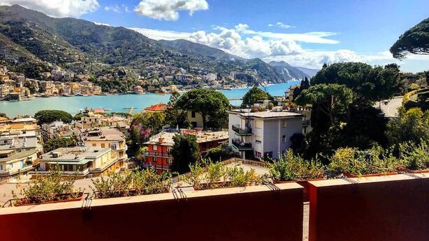 A coastal town with buildings overlooking a bay, surrounded by mountains.