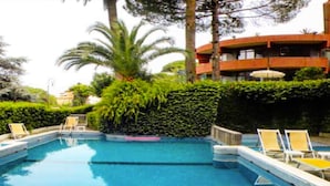 A swimming pool with lounge chairs and a building in the background.