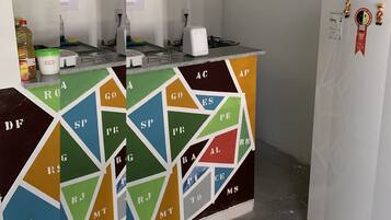A kitchen with a colorful geometric backsplash, a white refrigerator, and two hanging light fixtures.