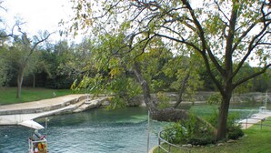 A park with a pond, a walking path, and a playground area. - The Tiny House in Travis Heights (Austin)