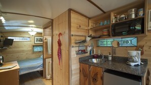 A compact kitchen with wooden cabinets, a microwave, and a coffee maker. - The Tiny House in Travis Heights (Austin)