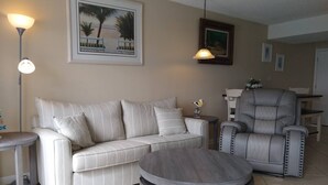 Un salon comprenant un canapé, un fauteuil, une table basse ronde et une lampe.