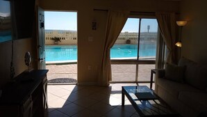 Une chambre avec vue sur une piscine, un canapé, une table basse et un téléviseur.