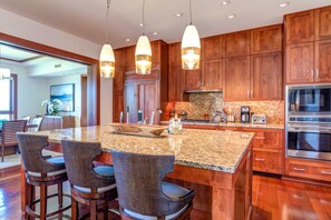 A modern kitchen with wooden cabinets, granite countertops, and stainless steel appliances.