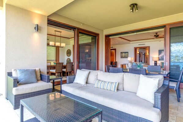 A spacious outdoor seating area with a sofa, chairs, and a glass-top table.