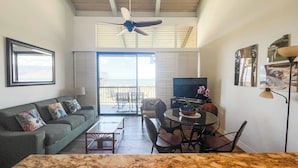 A living room with a sofa, TV, dining table, chairs, and a ceiling fan. - Luana Kai Resort D306 (Kihei)