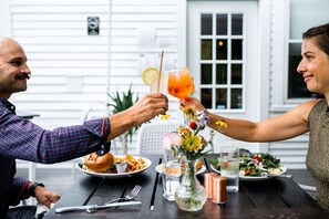 A dining table with plates of food, a drink, and a vase of flowers. - Craftsbury Farmhouse (Craftsbury)