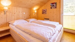 A wooden cabin room with two beds, a window with a view of a forest, and a wall-mounted sign. - Nice Chalet With Whirlpool (Sankt Georgen am Kreischberg)