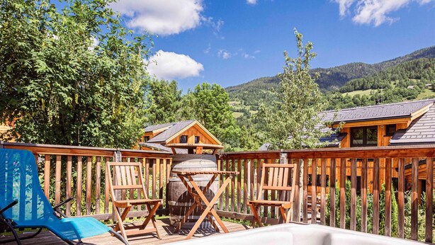 A hot tub with wooden deck chairs, a wooden barrel, and a view of a mountain landscape. - Nice Chalet With Whirlpool (Sankt Georgen am Kreischberg)