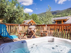 A hot tub with wooden deck chairs, a wooden barrel, and a view of a mountain landscape. - Nice Chalet With Whirlpool (Sankt Georgen am Kreischberg)