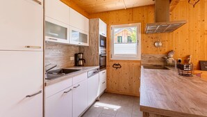 A compact kitchen with white cabinets, a coffee maker, a window, and a wooden ceiling. - Nice Chalet With Whirlpool (Sankt Georgen am Kreischberg)
