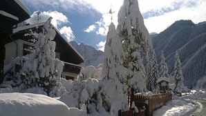 A snow-covered mountain landscape with a wooden cabin and snow-laden trees.