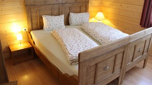 A wooden bed with floral bedding, two bedside lamps, and a nightstand. - Huge Apartment in Sankt Margarethen im Lungau near Ski Lift (Sankt Michael im Lungau)