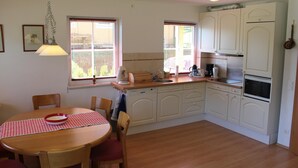 A compact kitchen with white cabinets, a wooden dining table with a checkered tablecloth, and a hanging light fixture. - Huge Apartment in Sankt Margarethen im Lungau near Ski Lift (Sankt Michael im Lungau)