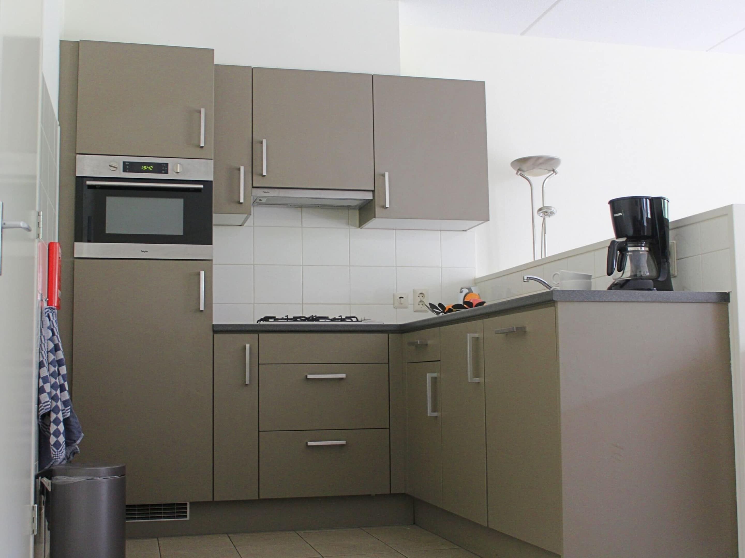 A compact kitchen with a microwave, stove, and coffee maker.