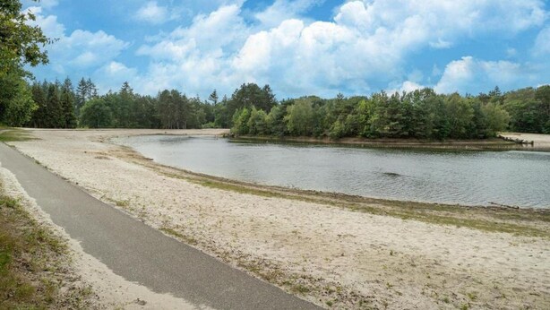 A sandy beach with a paved path and a lake surrounded by trees. - Relaxing Woodland Retreat (Rheezerveen)