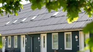 A row of motel rooms with individual doors, a small table with chairs, and a window with a basket on the windowsill. - Relaxing Woodland Retreat (Rheezerveen)