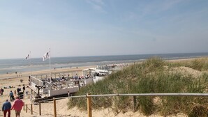 Eine Uferpromenade mit Aussichtsplattform, Sandstrand und dem Meer im Hintergrund.