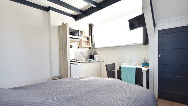Ein Schlafzimmer mit einem großen Bett, einem Schreibtisch und einer Küchenzeile.
