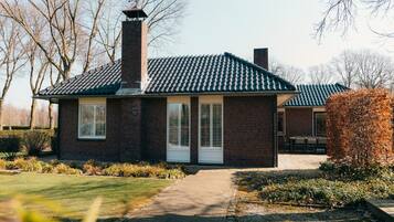Charming single-story cottage with a brick exterior, white-framed windows, and a small porch.