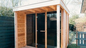 Une structure en bois dotée d’une porte en verre et d’un petit espace porche.