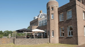 A large brick building with a prominent tower and a covered outdoor seating area.