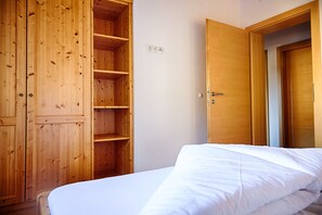 A room with a wooden wardrobe, a bed with white bedding, and a door with a handle. - Luxurious Apartment in Fugen With Sauna (Fuegenberg)