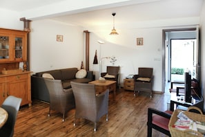 A living room with a sofa, chairs, a wooden cabinet, and a television. - Farmhouse Appartment in Eede (Eede)