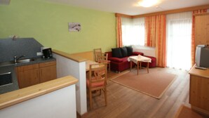 A compact living space with a kitchenette, a dining area, and a seating area with a sofa and chairs.