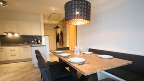 A modern dining area with a wooden table set for four, black upholstered chairs, and a unique patterned pendant light. - Vogue Apartment in Sankt Margarethen im Lungau near Ski Lift (Sankt Margarethen im Lungau)
