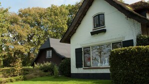 A white house with a dark roof, surrounded by greenery and trees. - Charming Holiday Home in Hulshorst With Pool (Hulshorst)