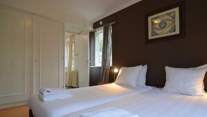 A hotel room with a large bed, a wardrobe, a window with curtains, and a framed picture on the wall. - Charming Holiday Home in Hulshorst With Pool (Hulshorst)