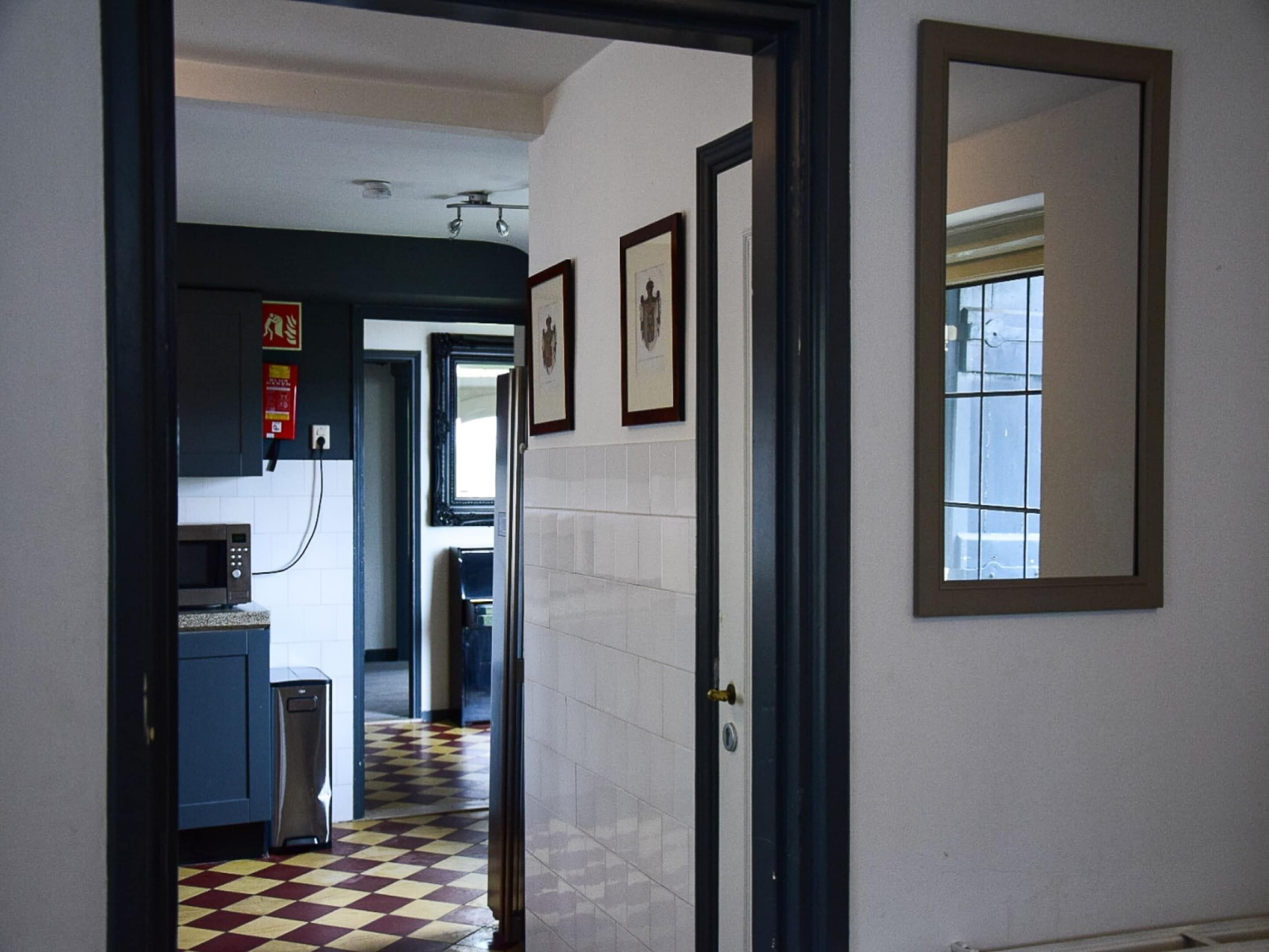 Un pasillo con piso a cuadros, un microondas y un lavabo en una kitchenette.