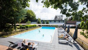 A swimming pool with lounge chairs and umbrellas, surrounded by a fence and greenery. - Charming Holiday Home in Hulshorst With Pool (Hulshorst)